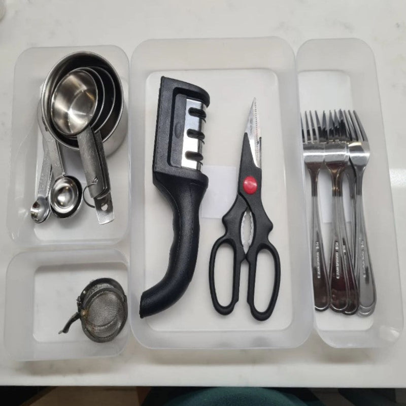 Set of kitchen utensils including measuring cups, a black kitchen tool, scissors, and forks on a white background.
