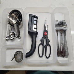 Set of kitchen utensils including measuring cups, a black kitchen tool, scissors, and forks on a white background.