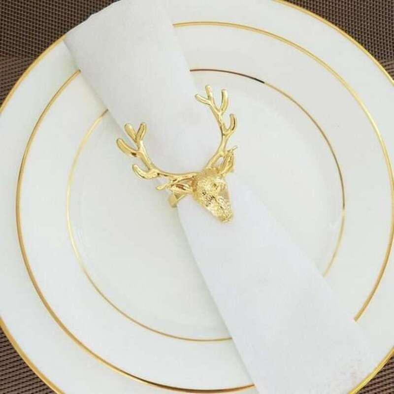 Gold deer head napkin ring on a white napkin with gold-rimmed plates.