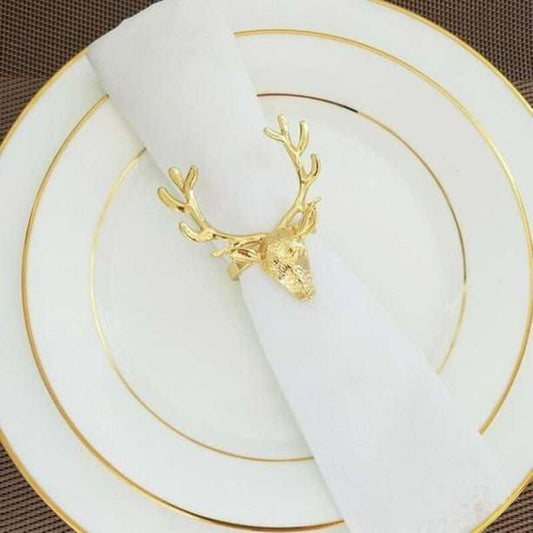 Gold deer head napkin ring on a white napkin with gold-rimmed plates.
