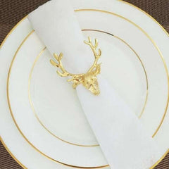 Gold deer head napkin ring on a white napkin with gold-rimmed plates.
